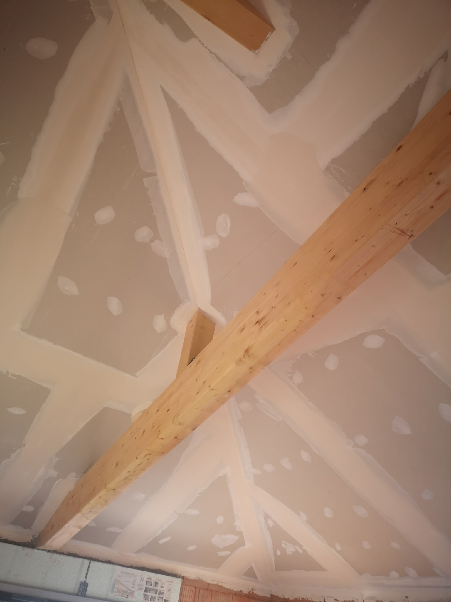 Unfinished room interior with white plastered walls and exposed ceiling in a construction site.
